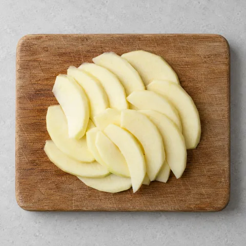 Thinly sliced peeled apples on a wooden cutting board.