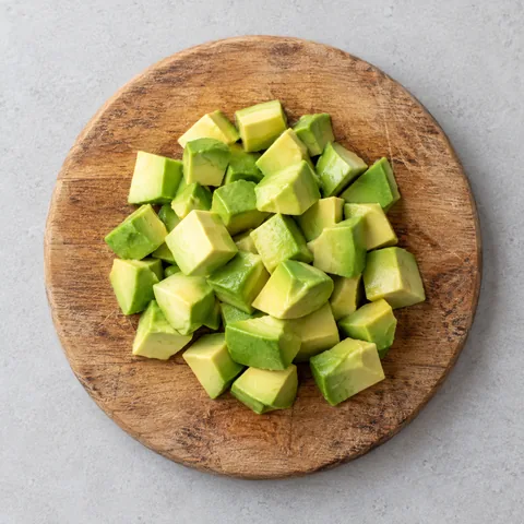 Diced ripe avocado on a wooden cutting board.