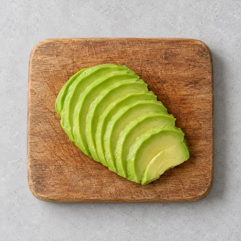 Sliced ripe avocado on a wooden cutting board.