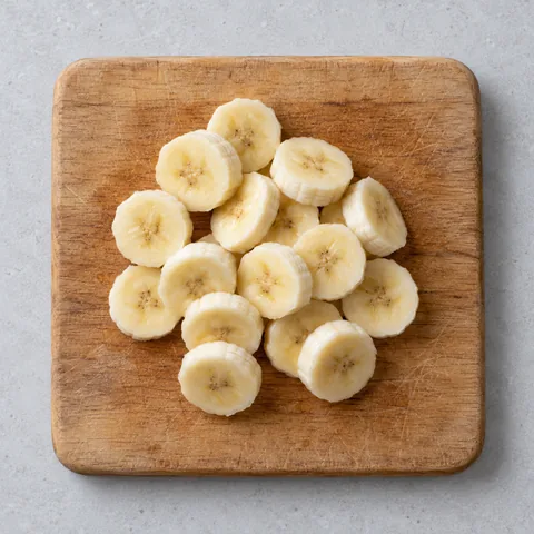 Sliced ripe banana on a wooden cutting board.