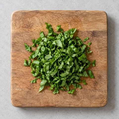 Chopped fresh basil on a wooden cutting board.