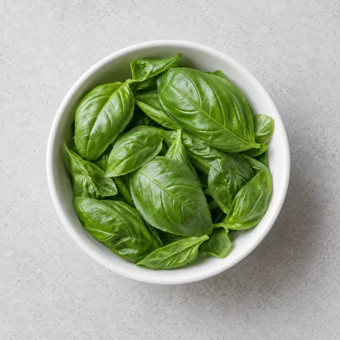 Fresh basil leaves in a small white bowl.