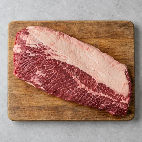 Raw beef brisket in one piece on a wooden cutting board.