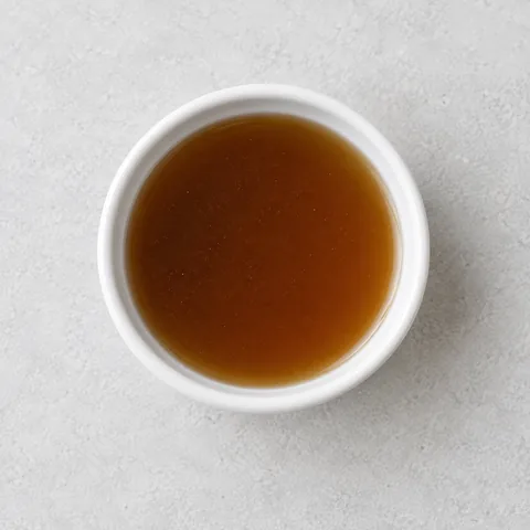 Beef broth in a small white ramekin.