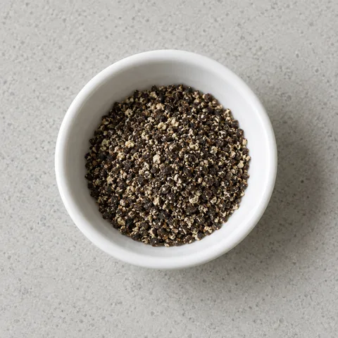 Freshly ground black pepper in a small white bowl.