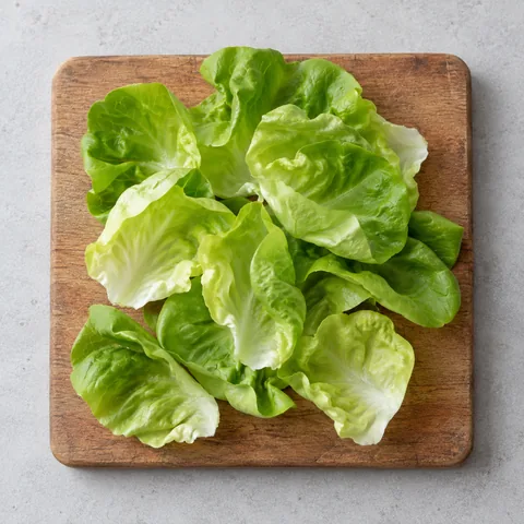 Butter lettuce leaves separated, washed and dried on a wooden cutting board.