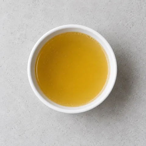 Chicken broth in a small white ramekin.