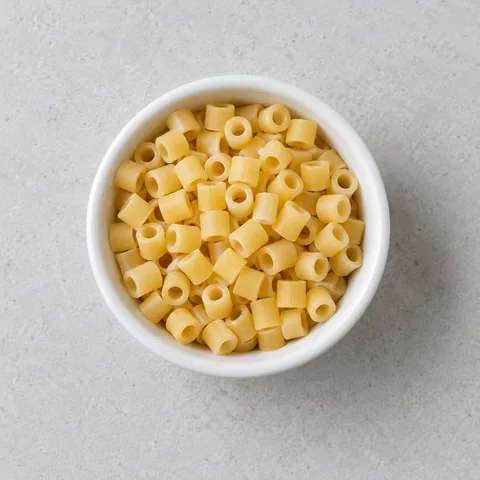 Dry ditalini pasta in a small white ramekin.