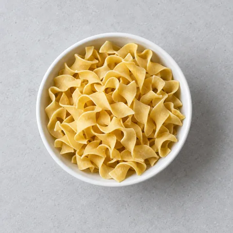 Dried wide egg noodles in a small white bowl.