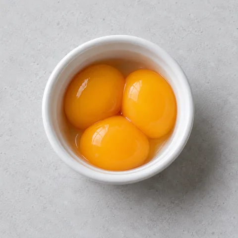 Raw egg yolks in a small white ramekin.