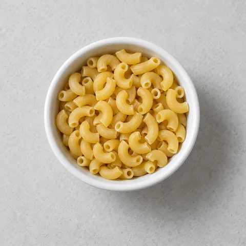 Dry elbow macaroni in a small white ramekin.