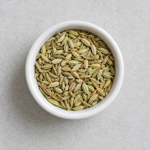 Whole fennel seeds in a small white ramekin.