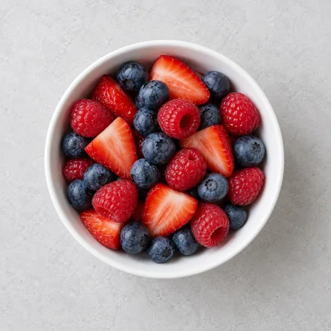 Mixed fresh berries in a small white bowl.