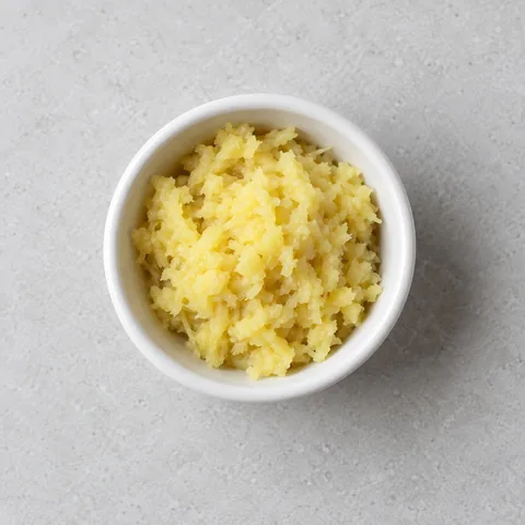 Finely grated fresh ginger in a small white ramekin.