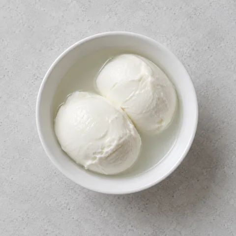 Fresh whole-milk mozzarella in a small white bowl.
