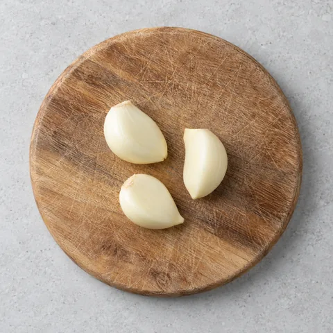 Peeled garlic cloves on a wooden cutting board.