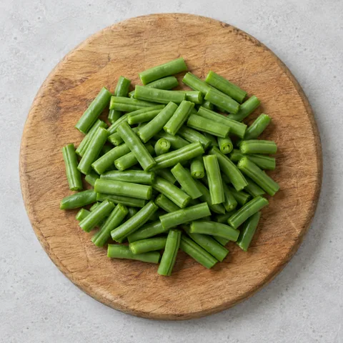 Trimmed green beans cut into short pieces on a wooden cutting board.
