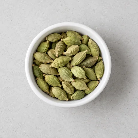 Green cardamom pods in a small white ramekin.