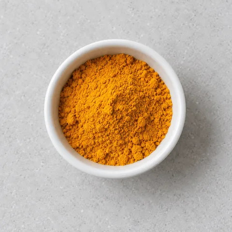 Ground turmeric in a small white ramekin.