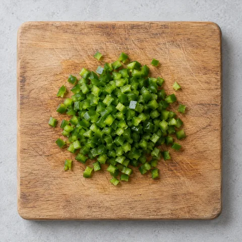 Seeded, finely chopped jalapeno on a wooden cutting board.