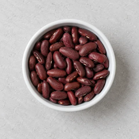 Dried red kidney beans in a small white ramekin.