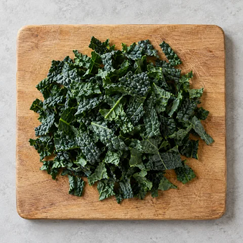 Stemmed and chopped lacinato kale on a wooden cutting board.