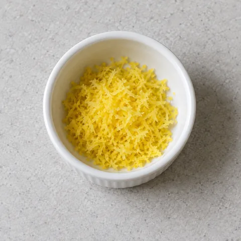 Finely grated yellow lemon zest in a white bowl.