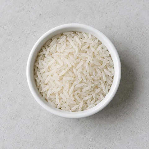 Uncooked long-grain white rice in a small white ramekin.