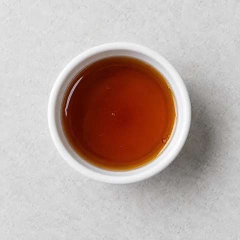 Pure maple syrup in a small white ramekin.