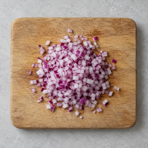 Finely chopped red onion on a wooden cutting board.