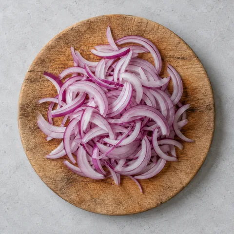 Thinly sliced red onion on a wooden cutting board.