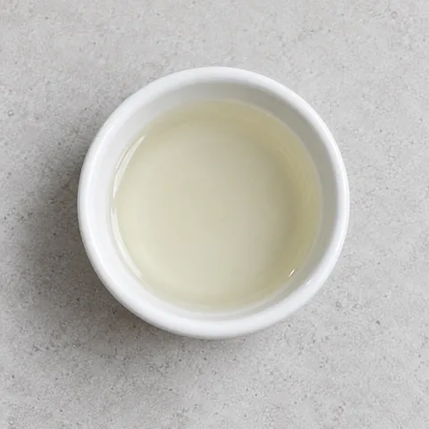 Unseasoned rice vinegar in a small white ramekin.