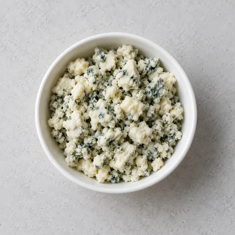 Crumbled Roquefort blue cheese in a small white bowl.