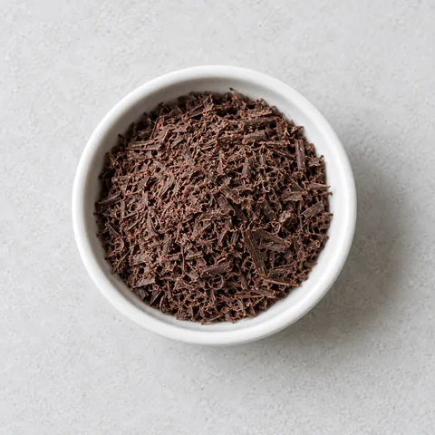 Grated semisweet chocolate in a small white ramekin.