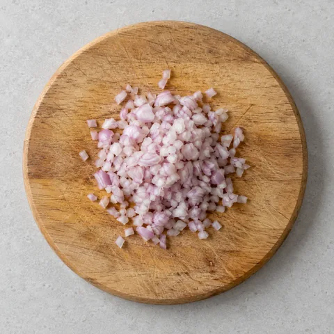 Minced shallot on a wooden cutting board.