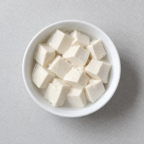 Silken tofu cut into small cubes in a small white bowl.