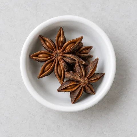 Whole star anise in a small white ramekin.