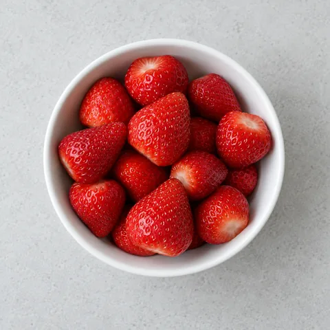 Hulled fresh strawberries in a small white bowl.
