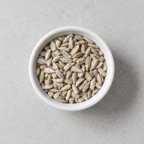 Hulled sunflower seeds in a small white ramekin.