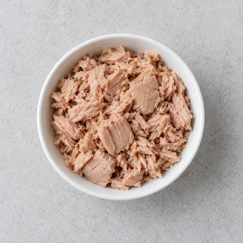 Drained oil-packed tuna in a small white bowl.