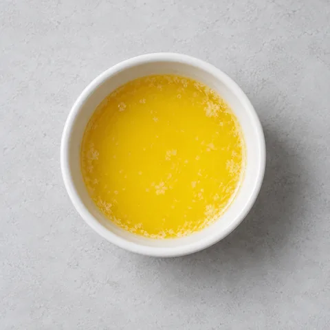 Melted unsalted butter in a small white ramekin.