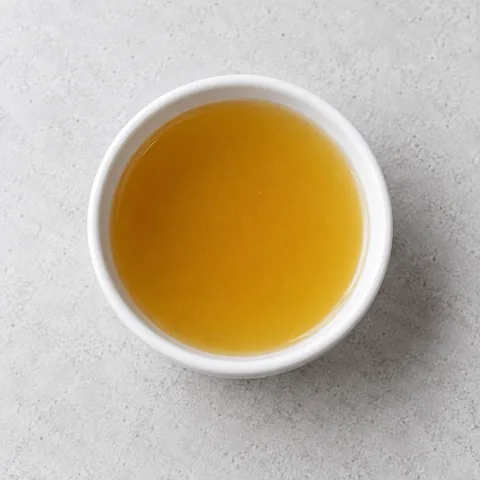 Vegetable broth in a small white ramekin.