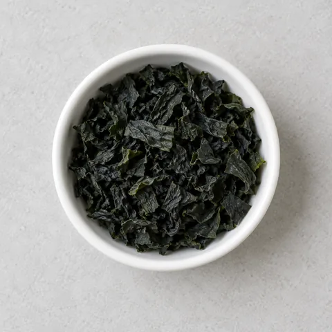 Dried cut wakame seaweed in a small white ramekin.
