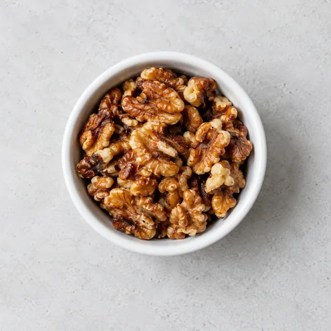 Toasted walnuts in a small white ramekin.