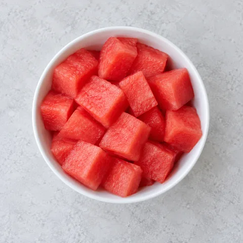 Seeded watermelon cubes in a small white bowl.