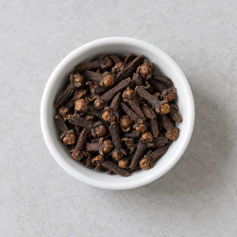 Whole cloves in a small white ramekin.