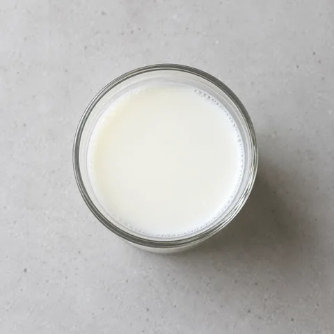 Whole milk in a small clear glass.