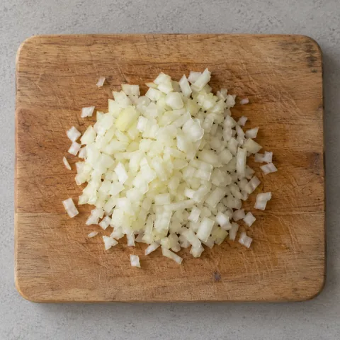 Finely chopped raw yellow onion on a cutting board.