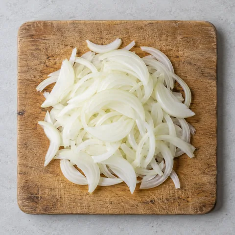 Thinly sliced yellow onion on a wooden cutting board.