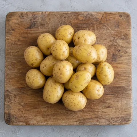 Small whole yellow-skinned Yukon Gold potatoes on a wooden cutting board.